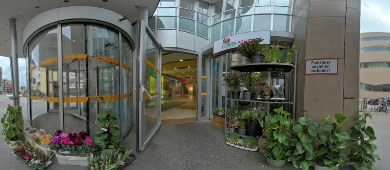 Eingang zum Kiesel-Einkaufszentrum mit Pflanzen und dem Flower-Power-Schild