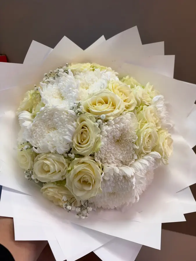 Weißer Strauß aus Rosen und Chrysanthemen in weißem Papier