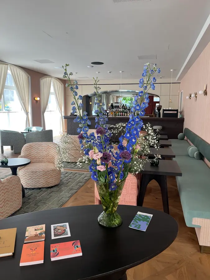 Gesteck mit blauem Rittersporn auf einem Tisch in einer Hotel-Lounge