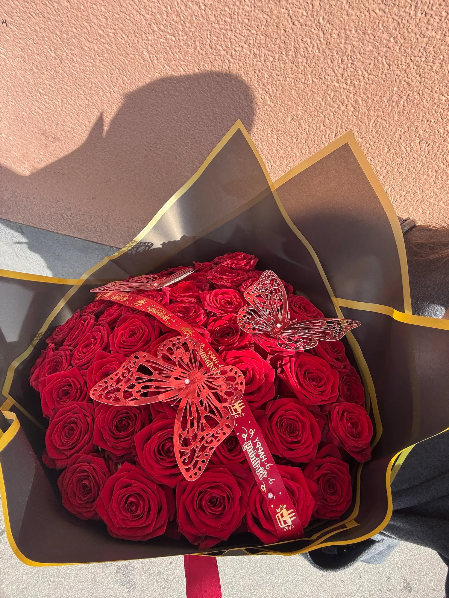 Großer Strauß roter Rosen mit Schmetterlings-Deko in schwarz-goldenem Papier